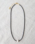 Minimalist dark brown cord choker necklace with a round glass pearl and gold-plated accents