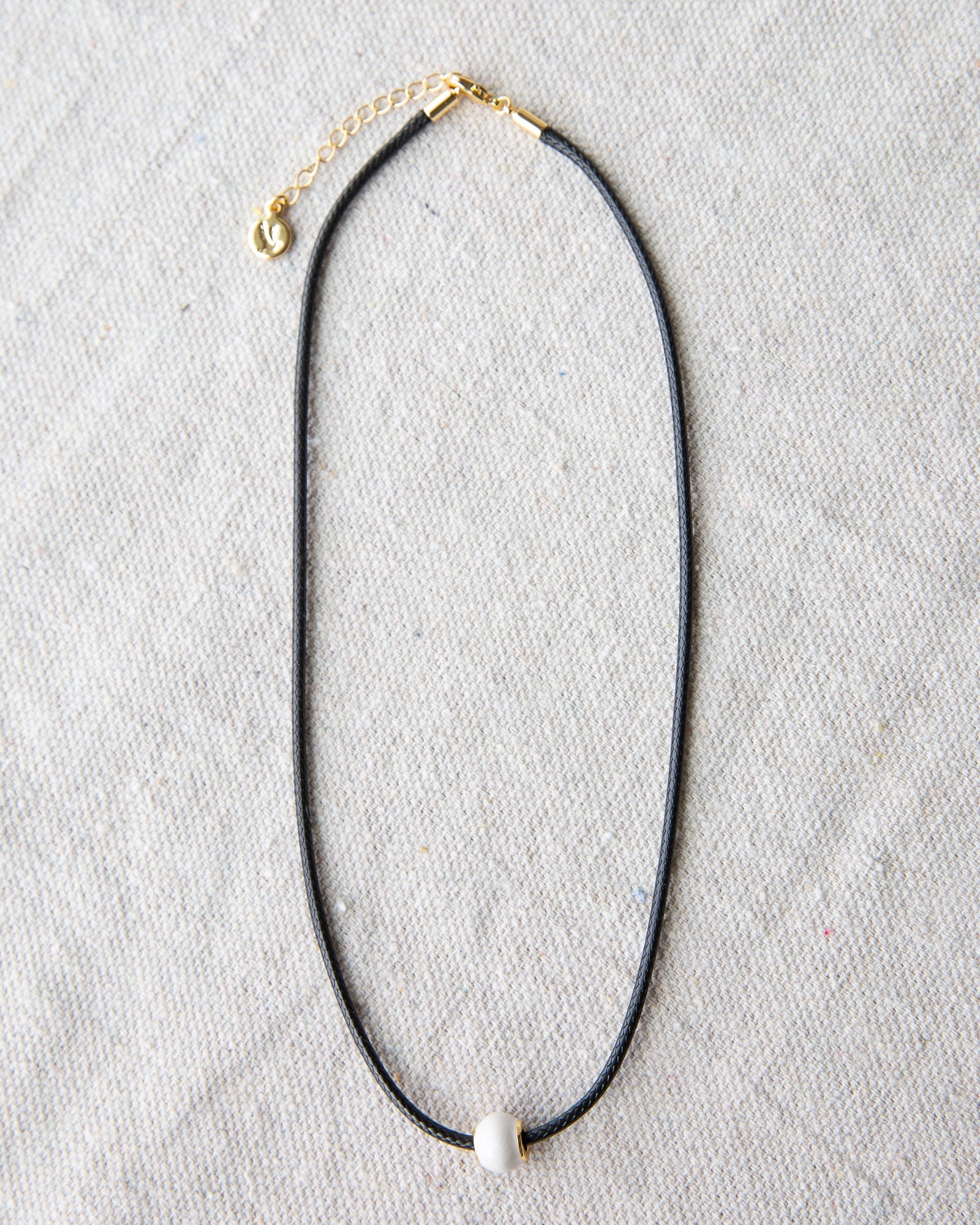 Minimalist dark brown cord choker necklace with a round glass pearl and gold-plated accents