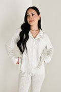 Model wearing a long-sleeve button-up lounge top and matching pants in a white, blue, and gold Dainty Vines pattern