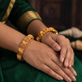 A set of heavy, gold-polished antique-style bangles with intricate traditional engravings.