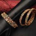 A set of two traditional Kemp-style bangles with vibrant red stones and gold accents.