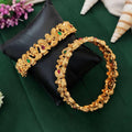 Temple-style gold polish bangles featuring Laxmi and peacock designs with stone embellishments.
