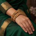 A pair of gold-toned Rajwadi polished bangles encrusted with decorative stones.