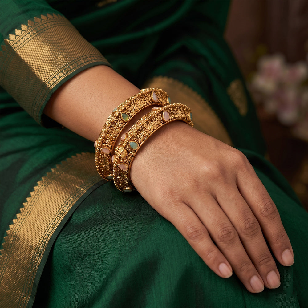 A pair of gold-toned Rajwadi polished bangles encrusted with decorative stones.