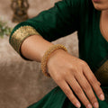 A close-up of a traditional stone-studded antique finish bangle set for ethnic wedding attire