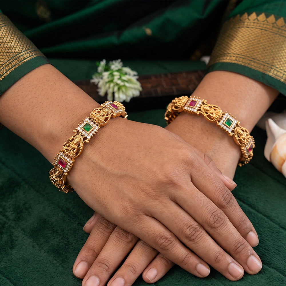 A pair of gold-toned temple design bangles featuring detailed Goddess Lakshmi motifs.
