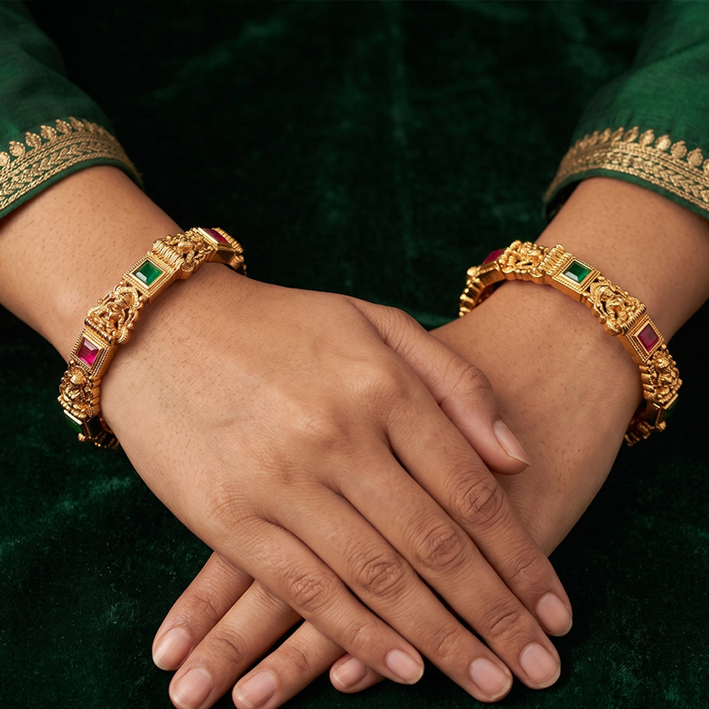 Traditional temple-style gold bangles featuring Lakshmi motifs and stone work