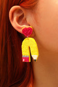 Close-up of a model wearing yellow heart and pencil-shaped beaded drop earrings.