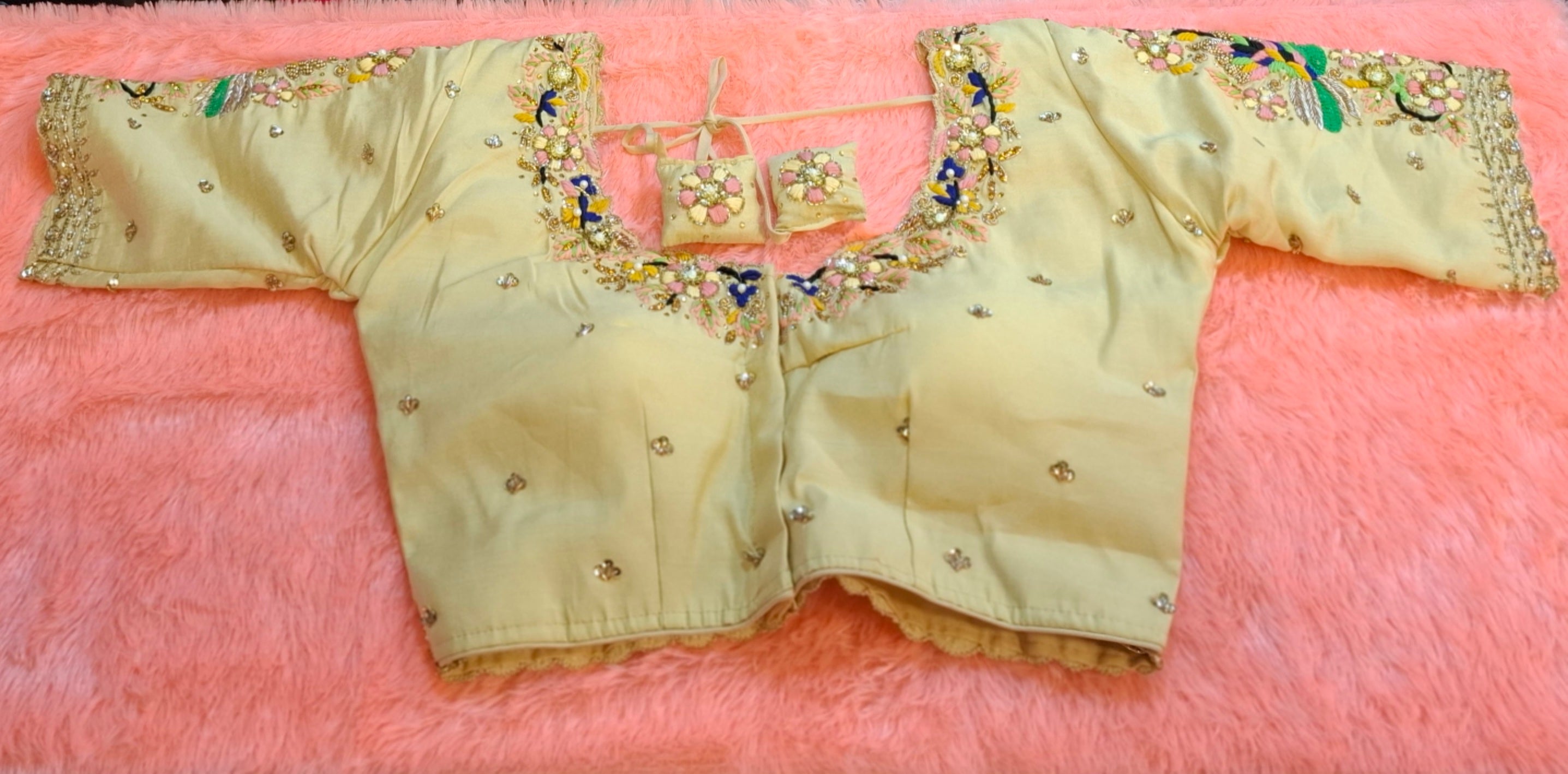 Close up of cream cotton silk readymade blouse with hand embroidered zardosi, beads, and sequin work.