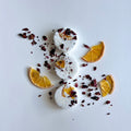 Three round white shower steamers decorated with dried orange slices and rose petals arranged on a white surface.