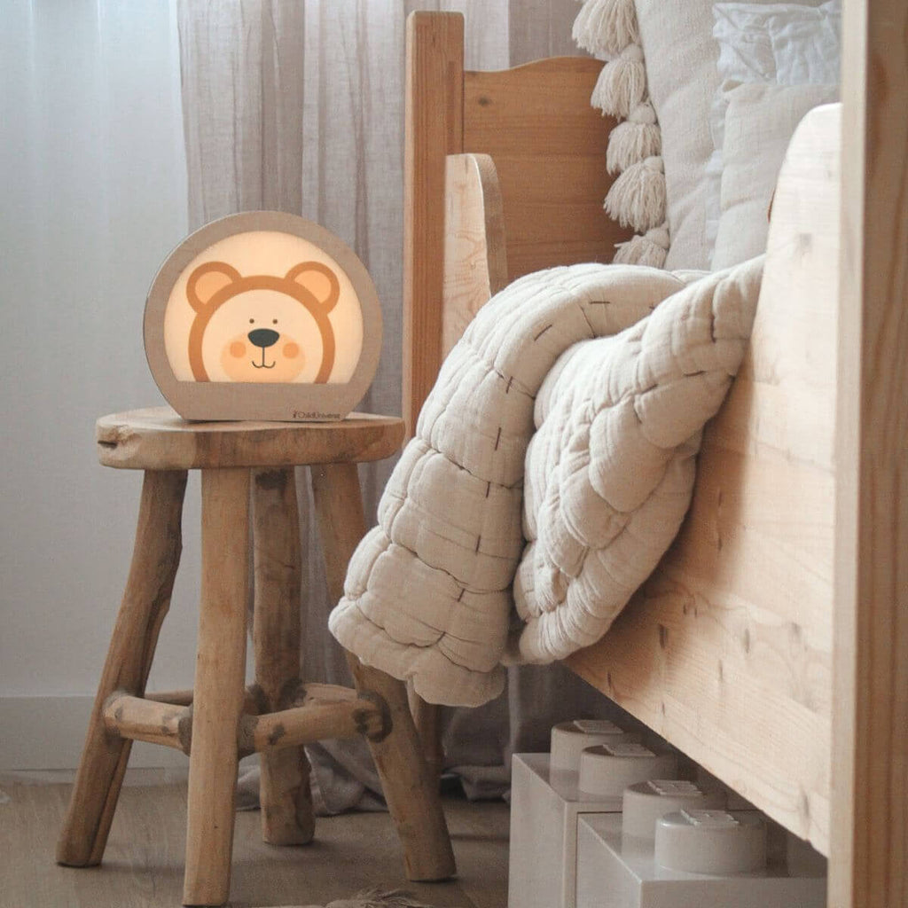 Minimalist bear-shaped LED night light in light-wood and white on a nursery nightstand