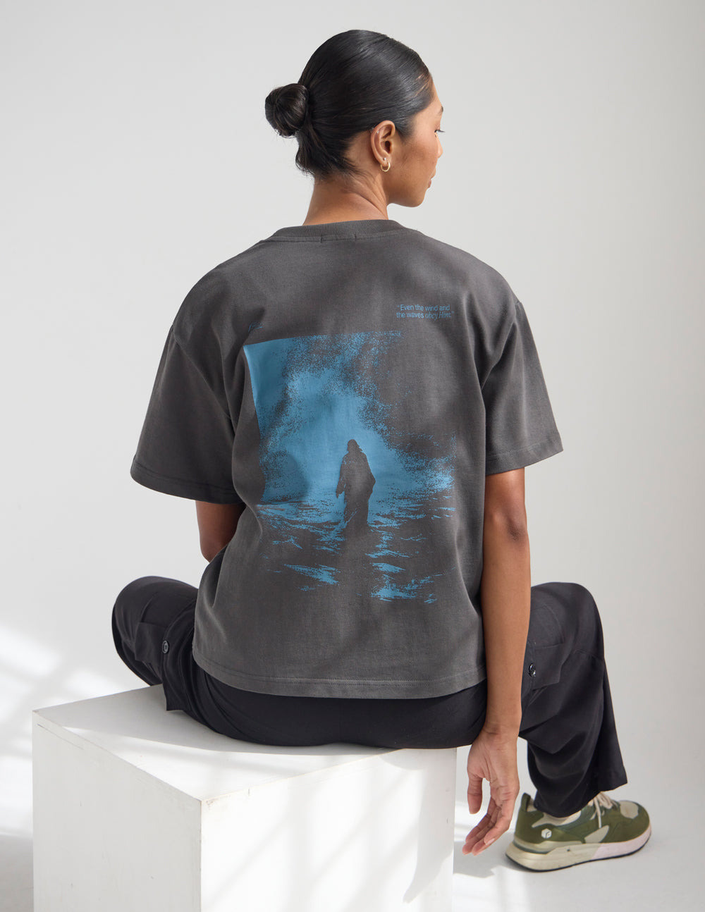 Model wearing a charcoal grey oversized heavyweight tee with slate blue graphic print, styled for a streetwear look.