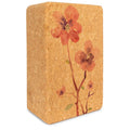 Tan and brown cork yoga block with a floral pattern and stylized lotus logo