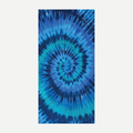 A vibrant blue and teal tie dye spiral pattern beach towel laying flat