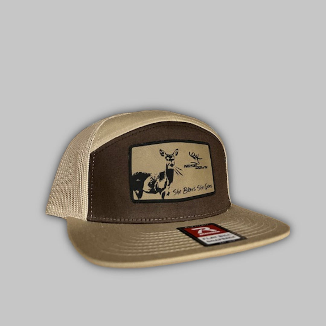 She Blows She Goes branded 7-panel camo flat-bill snapback hat.