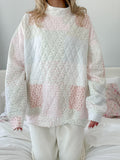 Model wearing an oversized quilted pastel mockneck sweatshirt with floral and striped patchwork patterns