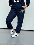 Women wearing navy Denver jogger sweatpants with pockets, white and red accents, and tapered ankle cuffs.