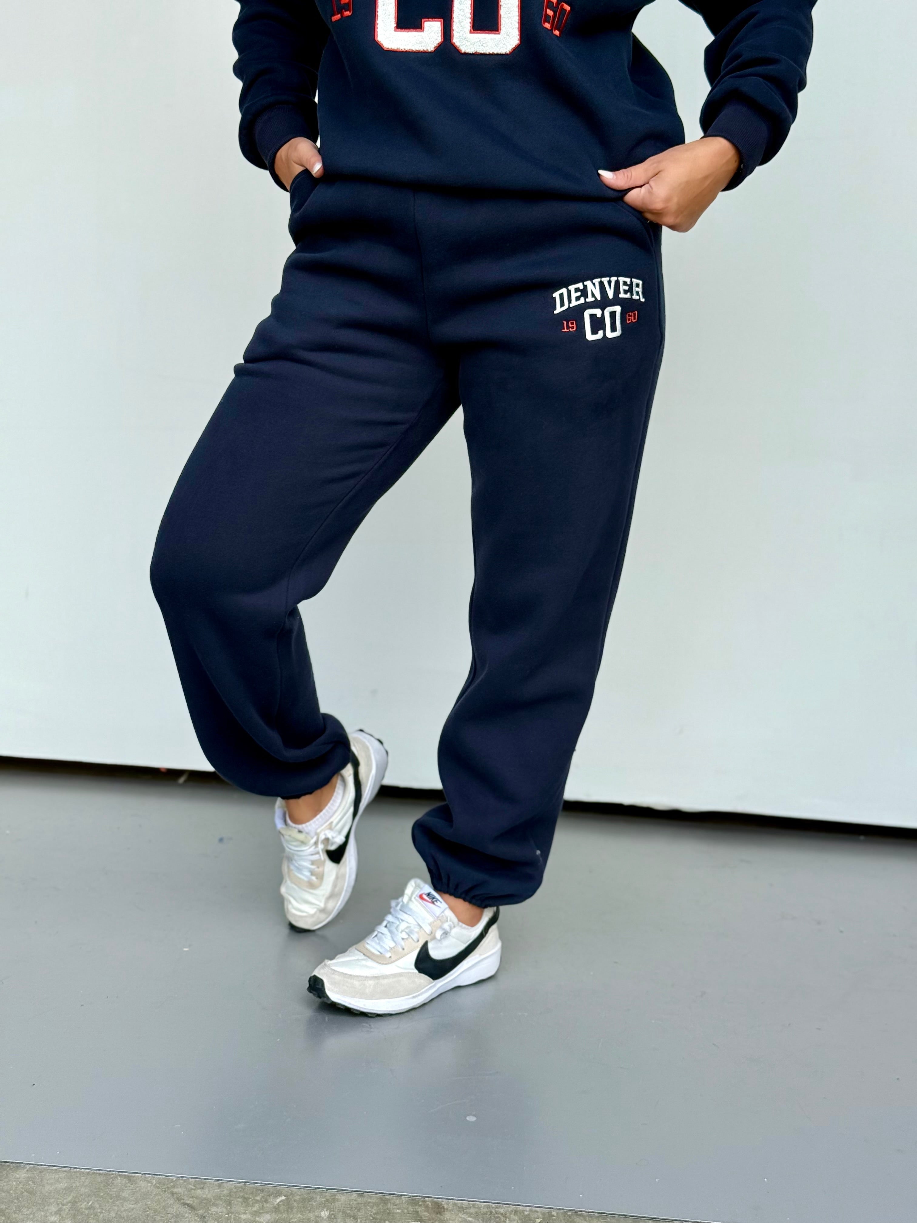 Women wearing navy Denver jogger sweatpants with pockets, white and red accents, and tapered ankle cuffs.