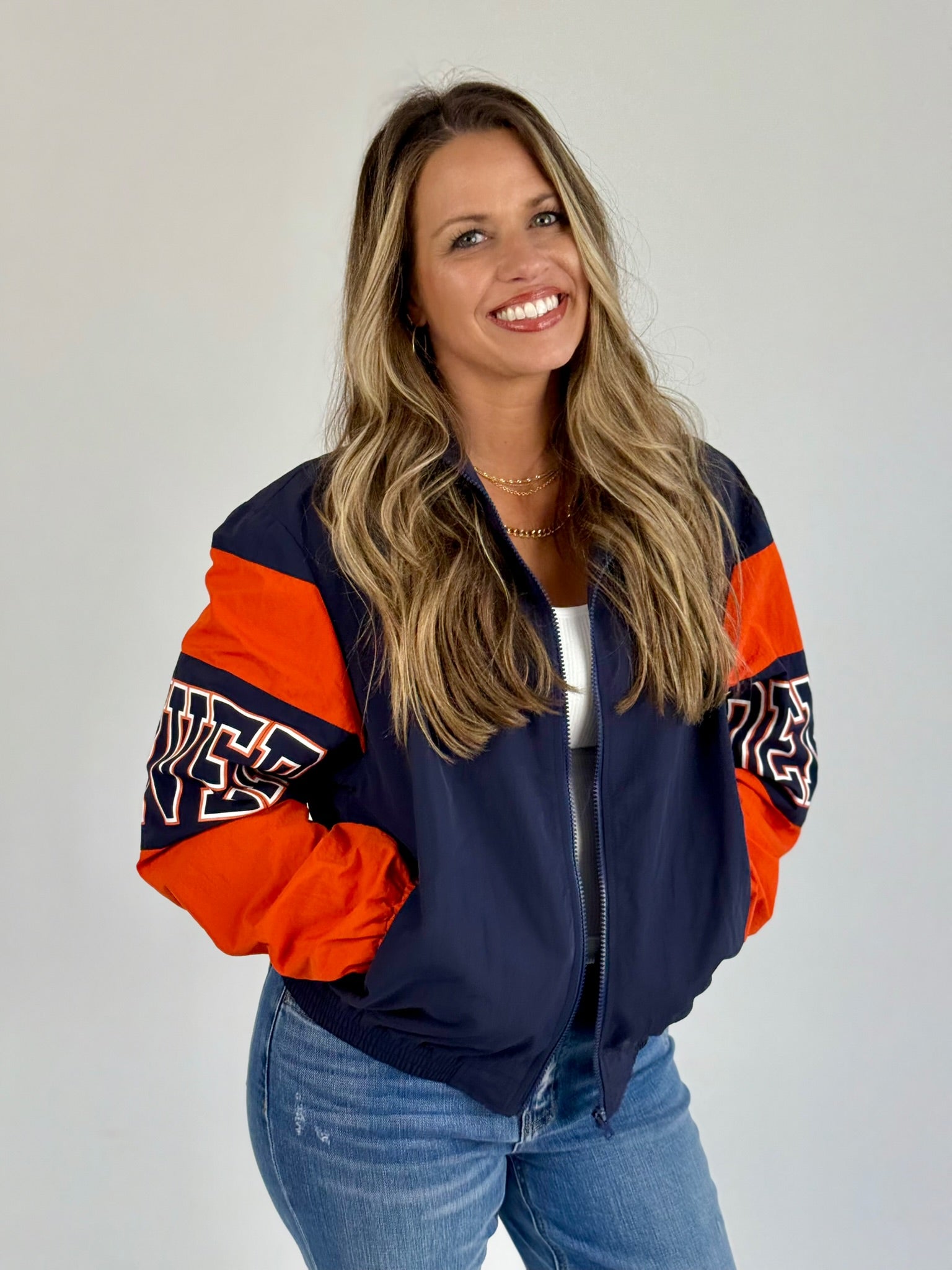 Women wearing a navy and orange Denver Retro bomber jacket with zip closure and sporty lettering.
