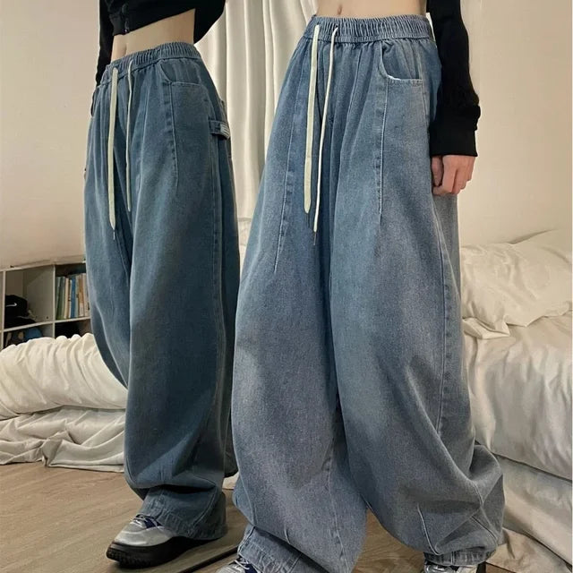 A woman wearing Harajuku style vintage baggy light blue denim jeans with an elastic drawstring waist and wide legs, styled for a street-style look.