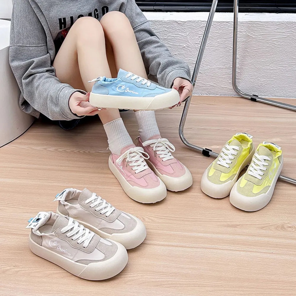 A collection of women's chunky platform sneakers in pastel blue, pink, light green, and beige, displayed on a wooden floor.
