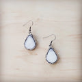 A pair of sparkling white druzy teardrop earrings with silver-tone trim on a wooden background