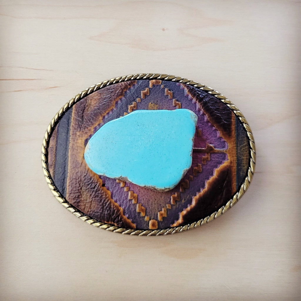 Oval leather belt buckle with magenta geometric inlay, blue turquoise stone center, and brass rope edge detail.