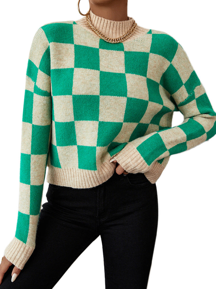 Woman wearing a green and beige checkerboard knitted mock neck pullover sweater with black jeans, showing a loose fit and ribbed cuffs and hem.