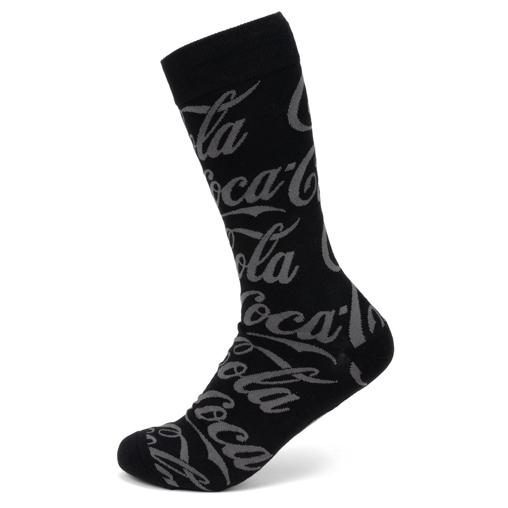 A pair of black crew socks featuring a repeated gray Coca-Cola script logo pattern.