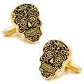 A pair of gold and black Day of the Dead sugar skull shaped cufflinks on a white background.