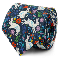 A navy blue men's necktie decorated with a white rabbit and colorful floral pattern, shown in a rolled detail shot and on a mannequin.