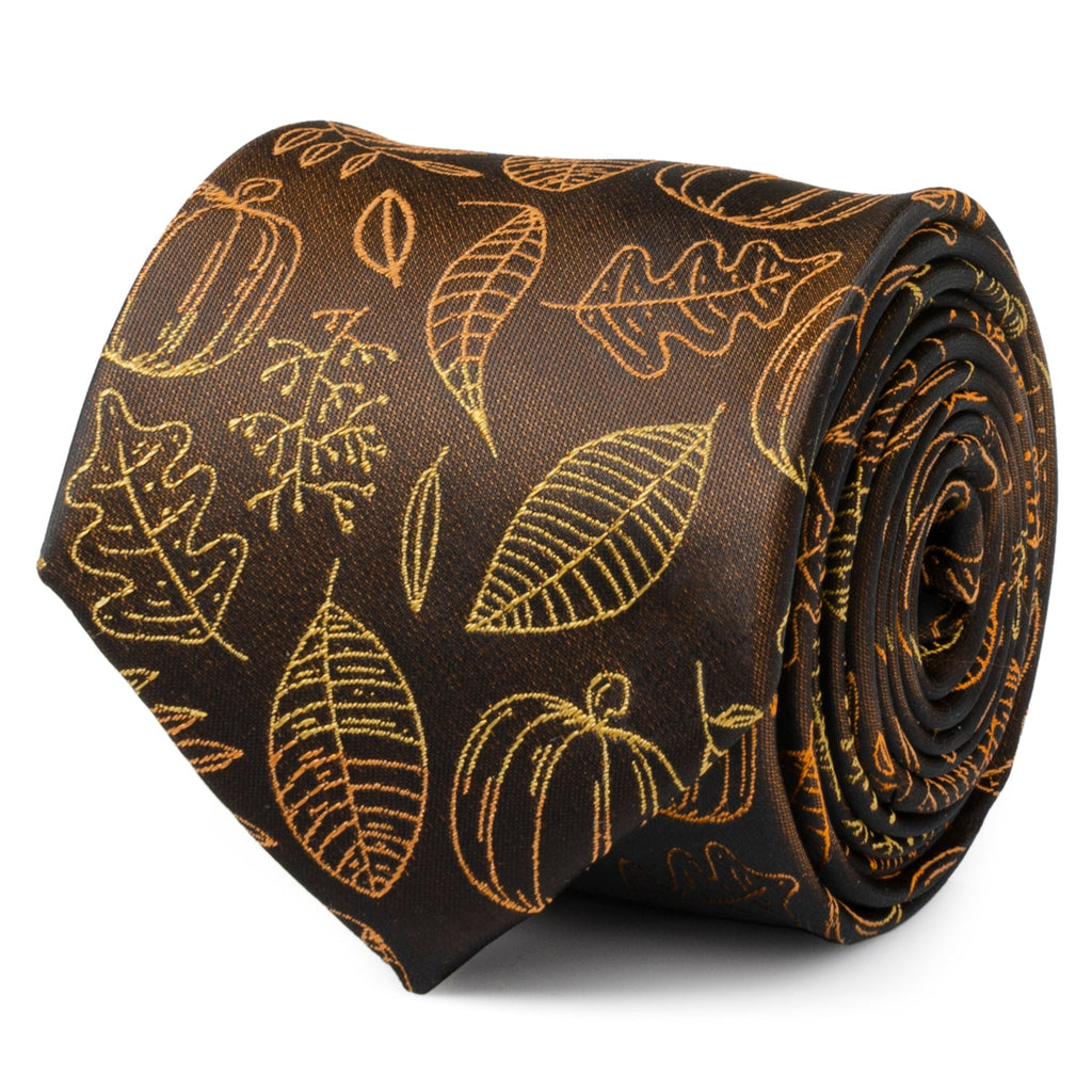 Close-up of a brown necktie with an orange printed pattern of pumpkins and leaves, tied in a knot against a white shirt and brown suit jacket.
