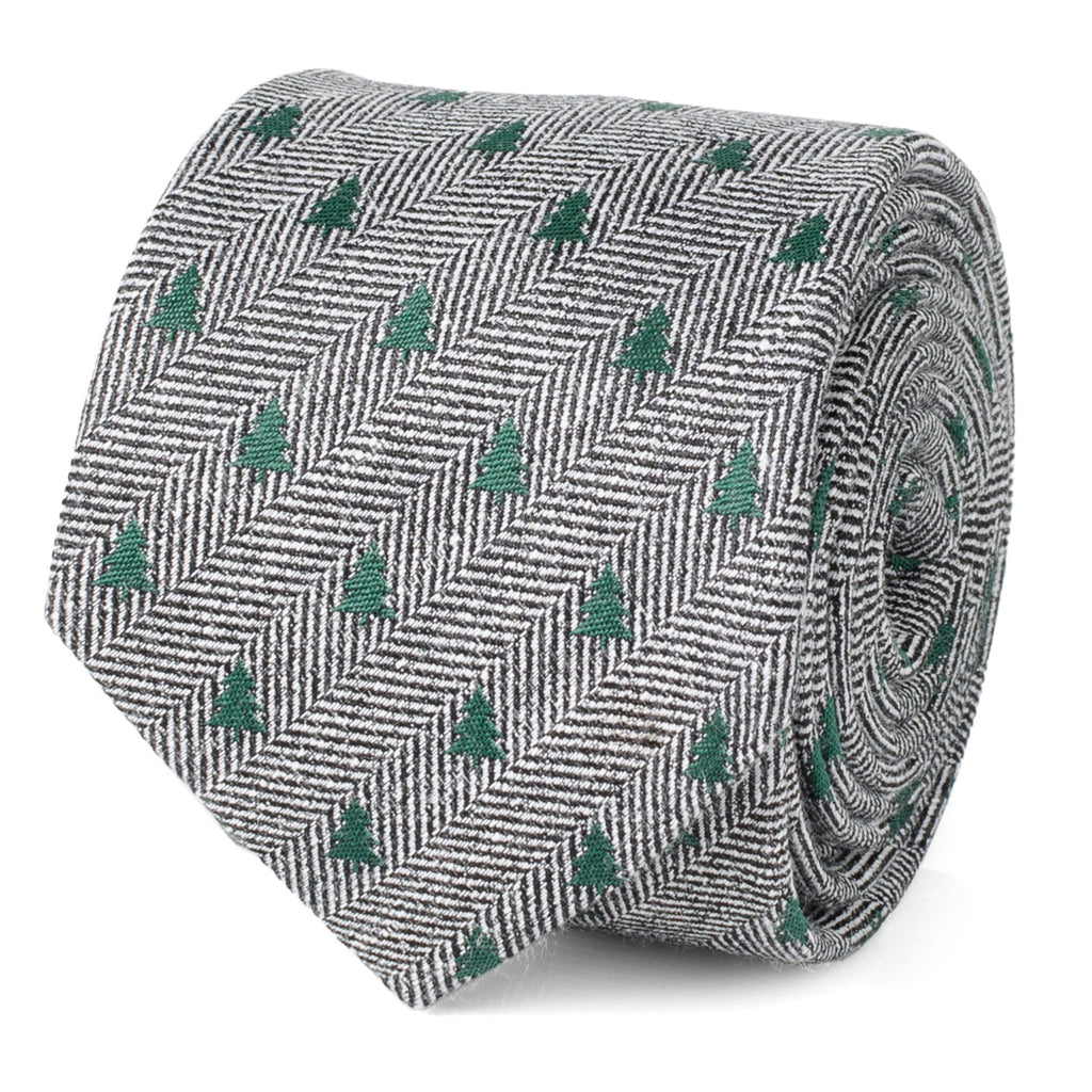 Close-up of a grey and white herringbone necktie featuring small green Christmas tree patterns, shown tied on a mannequin.