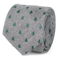 Close-up of a grey and white herringbone necktie featuring small green Christmas tree patterns, shown tied on a mannequin.