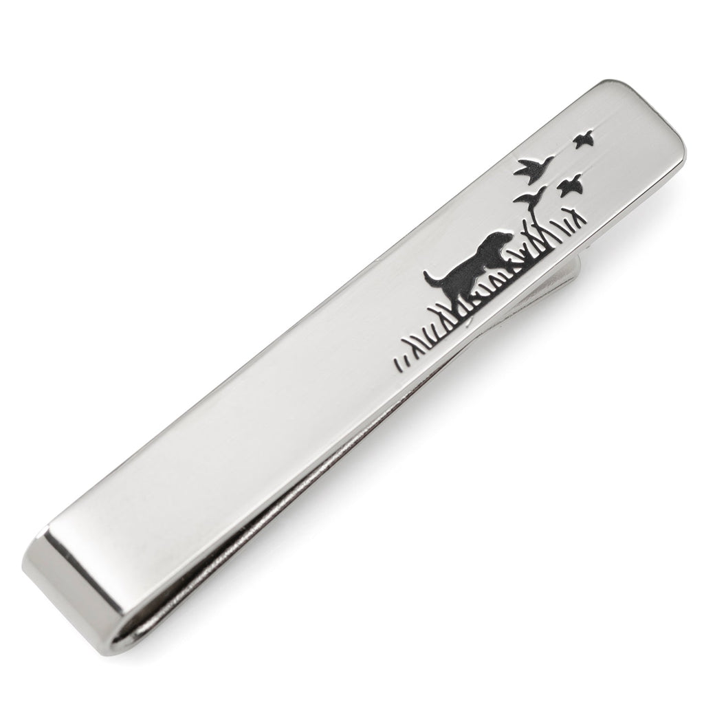A silver tone tie bar featuring a hunting dog silhouette design, shown pinned to a blue patterned tie.