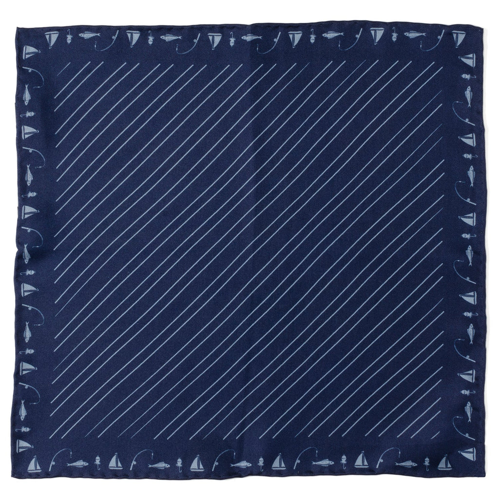 A navy blue silk pocket square with a light blue diagonal stripe and a border pattern of sailboats, fishing poles, and fish.