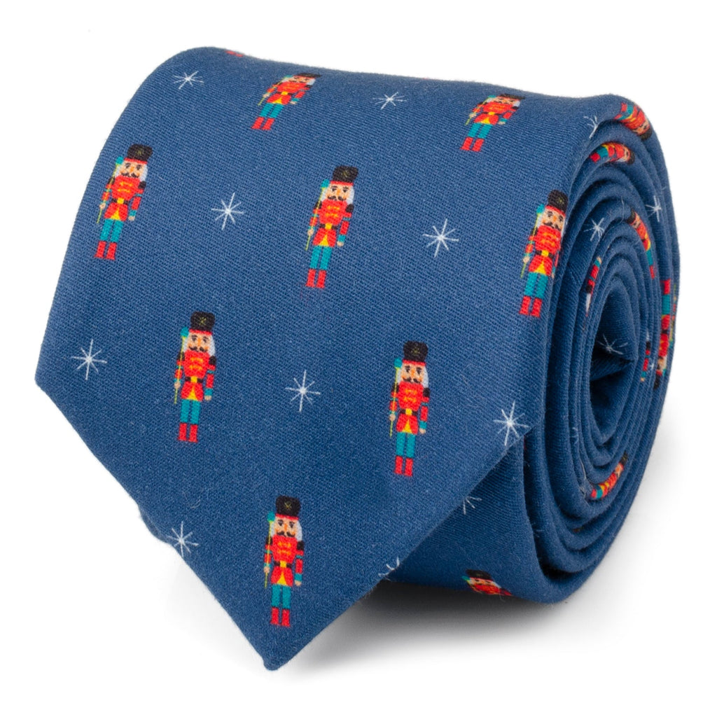 Navy blue men's necktie featuring a repeating holiday print of colorful nutcracker figures and white star icons.