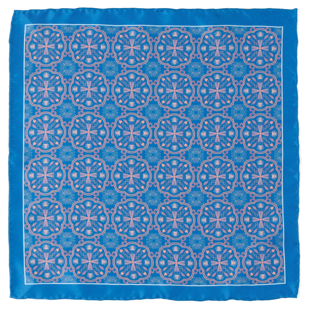 Blue silk pocket square featuring a repetitive Aboriginal-inspired pink ornament pattern folded in a suit pocket