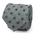 Close up and worn view of a gray herringbone necktie with small green shamrock patterns.
