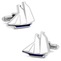 A pair of silver tone cufflinks featuring a sailboat design with white sails and a navy blue hull on a white background.