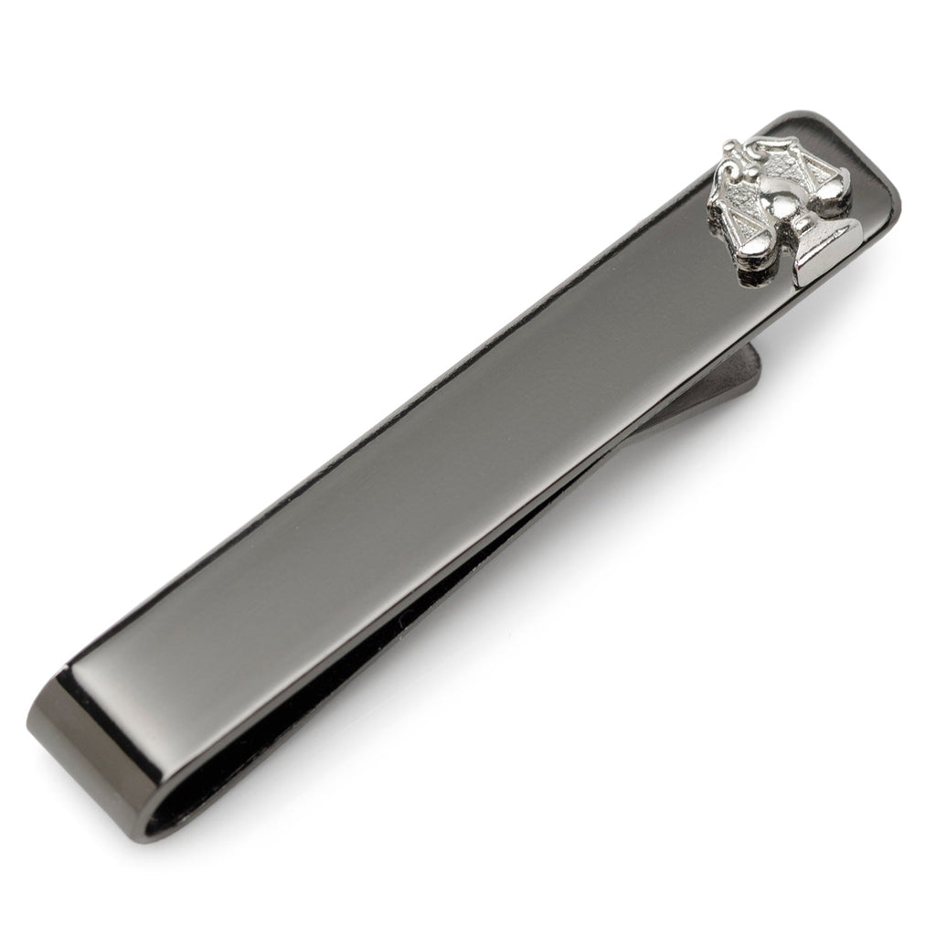 Close-up of a gunmetal Scale of Justice tie bar clipped onto a blue patterned necktie