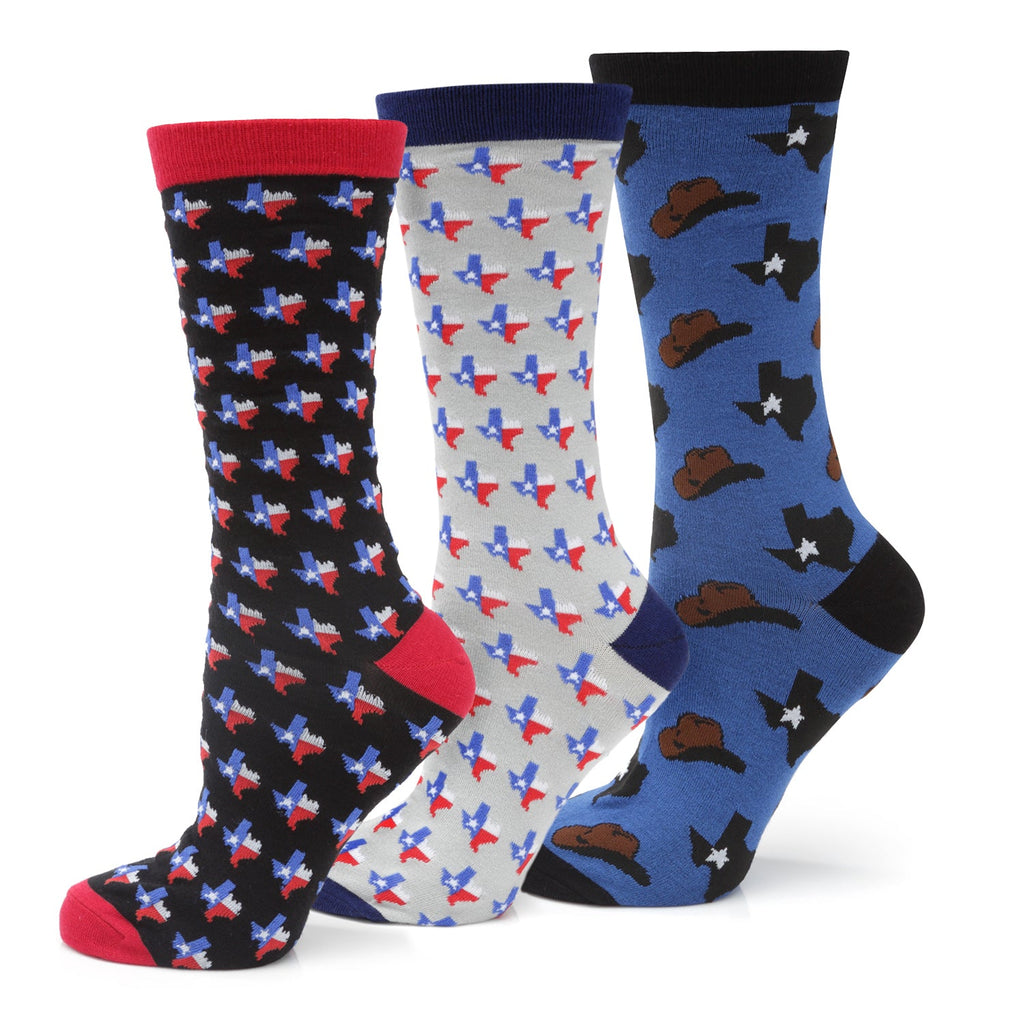 Three pairs of Texas-themed crew socks, including flag and cowboy hat designs, displayed with a gift box.
