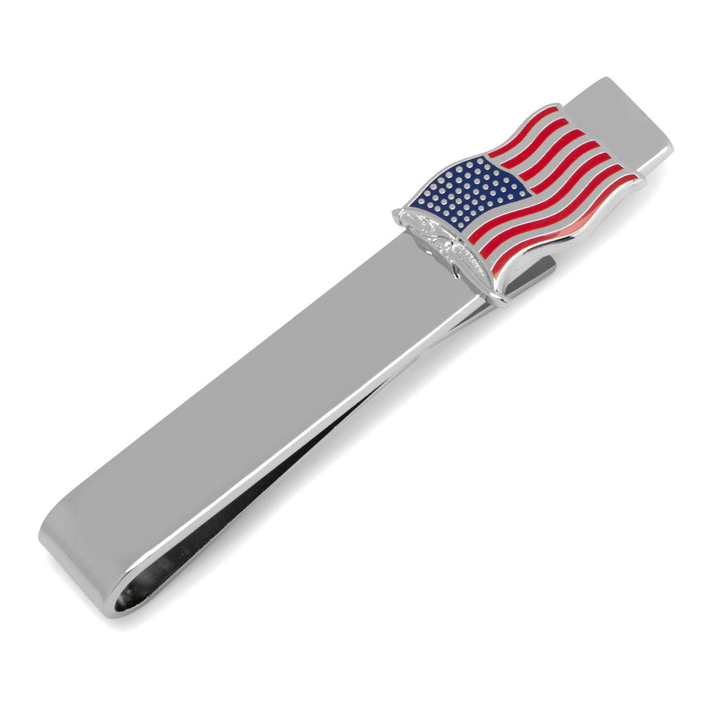 Close up view of a silver tone tie bar featuring a small waving American flag design with red, white, and blue enamel detail.