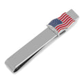 Close up view of a silver tone tie bar featuring a small waving American flag design with red, white, and blue enamel detail.
