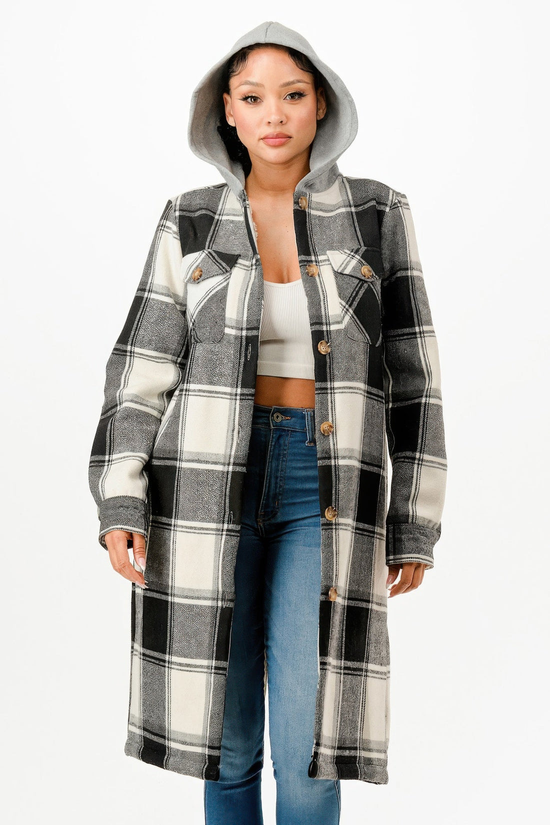 Model wearing a black and white hooded plaid long coat with a button-up front over a white top and blue jeans