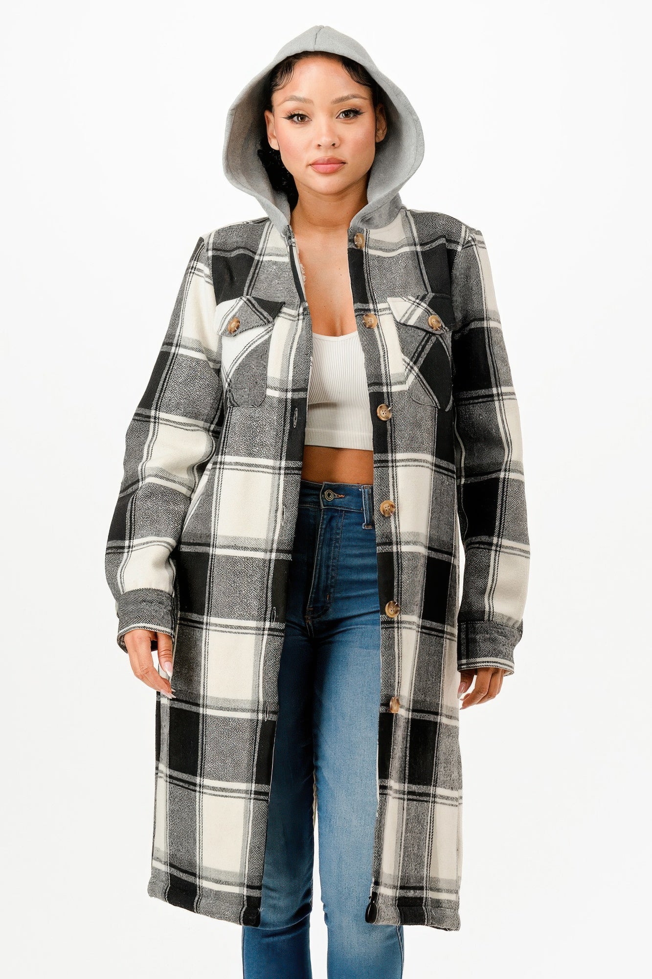 Model wearing a black and white hooded plaid long coat with a button-up front over a white top and blue jeans