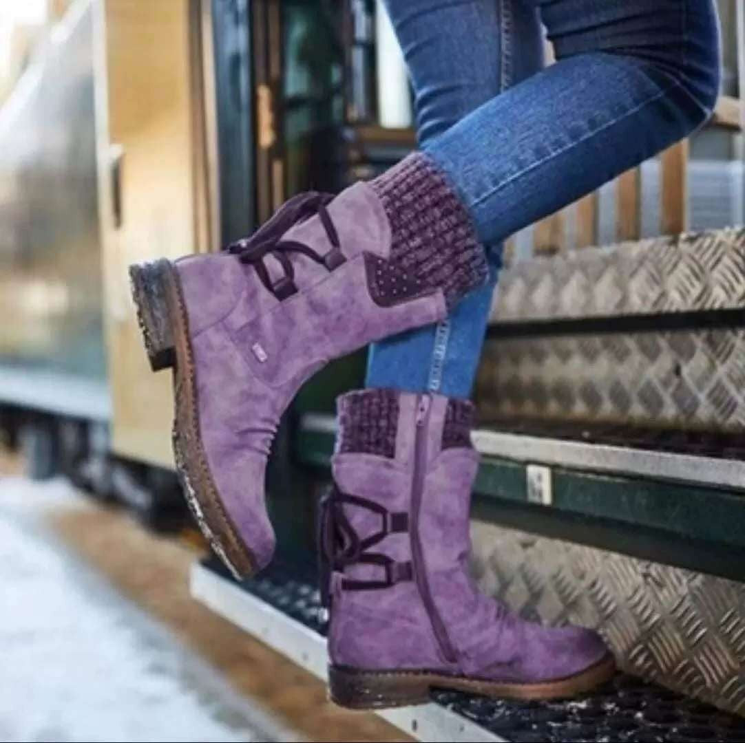 A pair of mid-calf boots with lace-up detail and a knit cuff worn with blue jeans