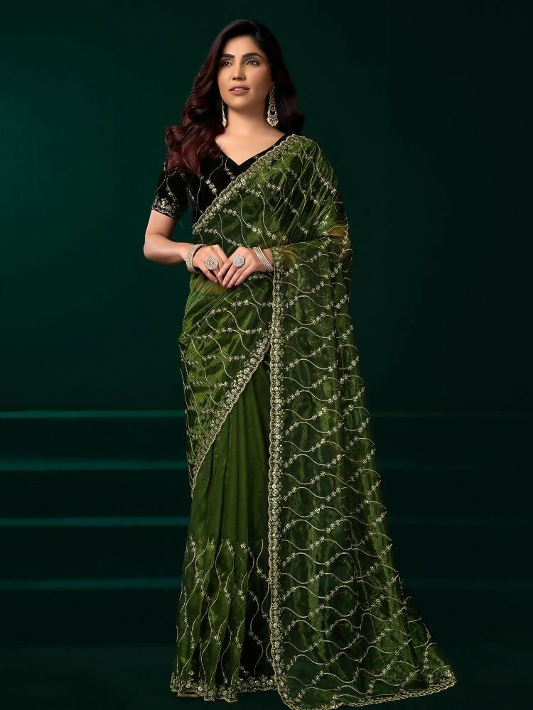 Woman wearing a vibrant green net party wear saree with a contrasting black velvet blouse