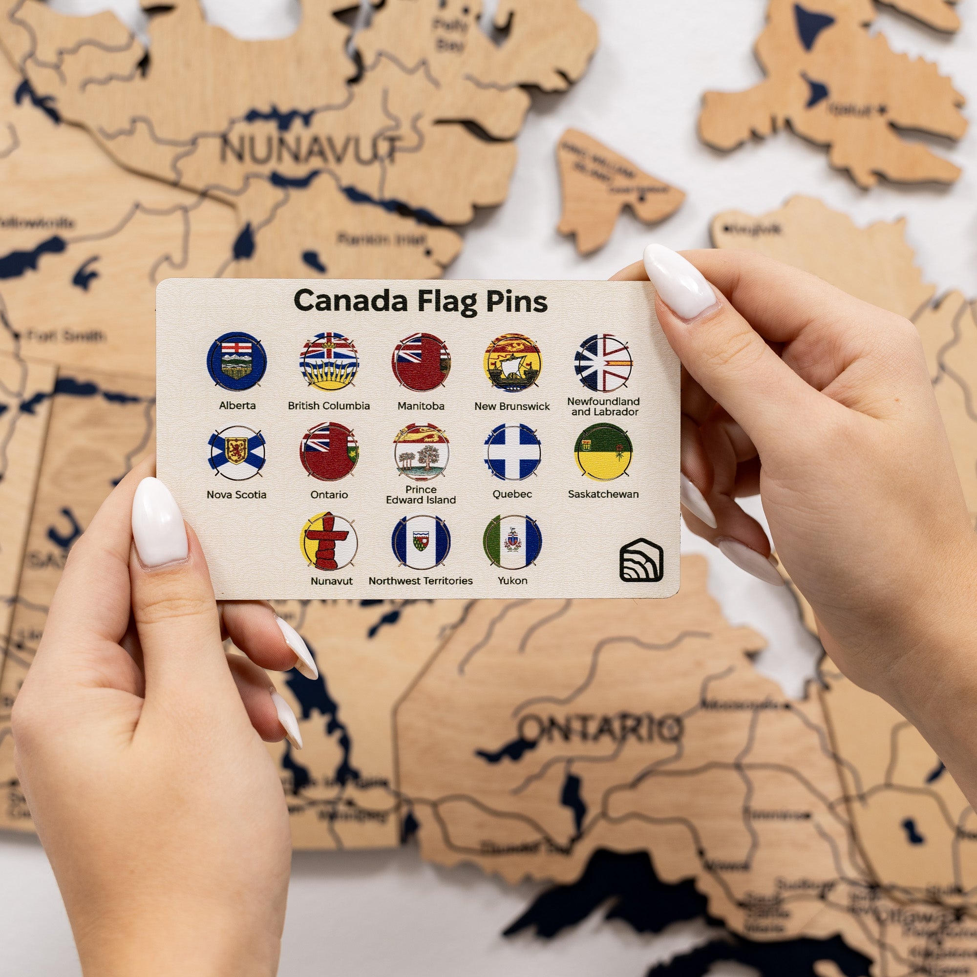 Set of 13 colorful Canadian province wooden pins displayed on a white backing card