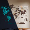 Luminous 3D wooden world map in brown, tan, and blue hues mounted on a white wall.